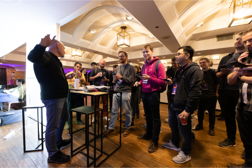 Attendees standing with drinks around high tables at the evening social.